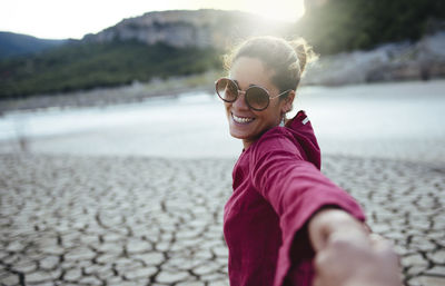 Smiling woman holding her hand for her boyfriend looking at the camera