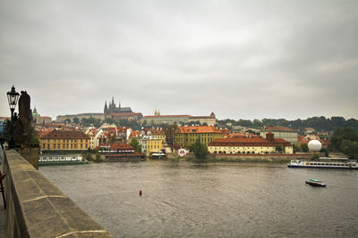 Buildings by river against sky