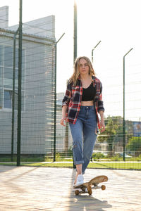 Full length of young woman with arms raised against sky