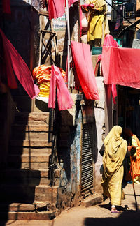 Woman in sari walking below laundry hanging over street in town