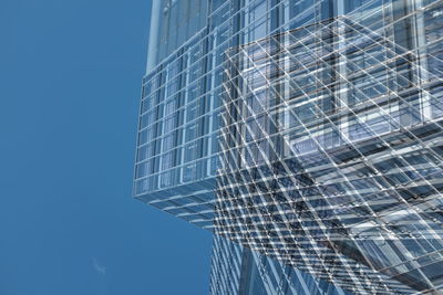 Double exposure of modern building against clear blue sky
