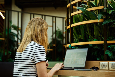 Rear view of woman using laptop at table