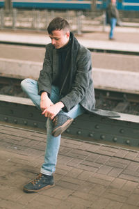 Full length of young man sitting outdoors