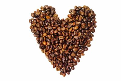 Heart shape coffee beans against white background