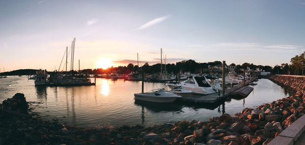 Boats moored at harbor against sky during sunset