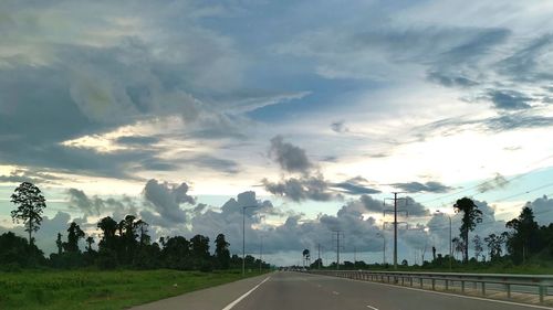 Road by trees against sky