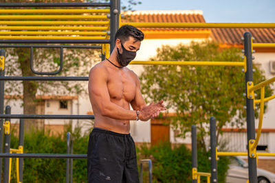 Full length of shirtless man standing against railing