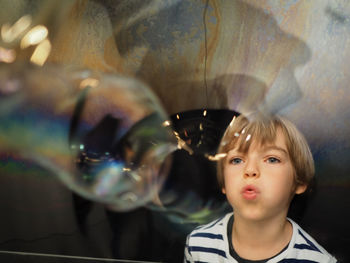 Boy playing with bubbles standing at railing