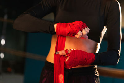 Midsection of woman wearing boxing gloves