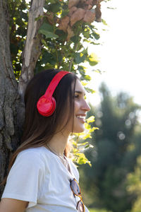 Portrait of young woman standing against tree