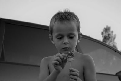 Close-up of shirtless boy looking at roasted marshmallow