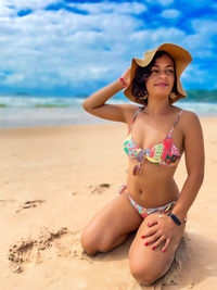 Portrait of young woman in bikini standing at beach