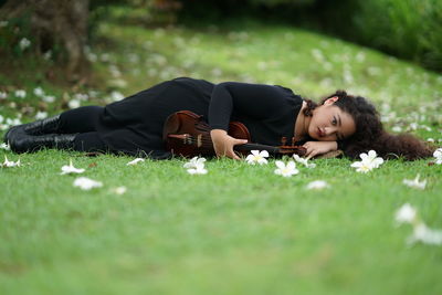 Young woman with violin lying on grass
