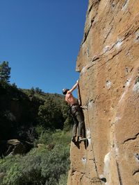 Low angle view of man climbing on rock