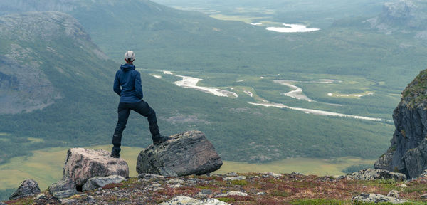 Man standing on rock looking at mountains