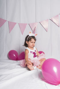 Portrait of cute girl with pink balloons on bed