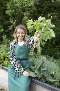 Portrait of smiling woman standing against plants