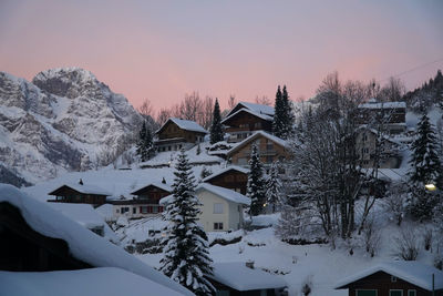 Snow covered houses in town during sunset