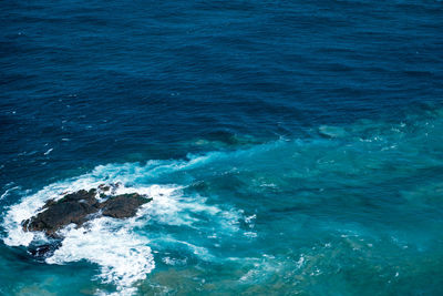 High angle view of sea with waves crashing against rocks