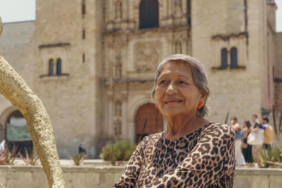 Portrait of young woman standing against building