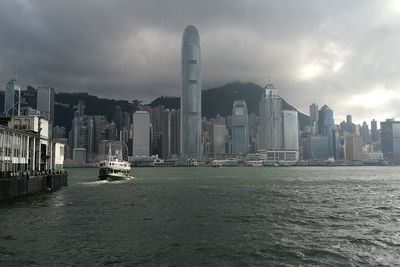 View of buildings by sea against cloudy sky