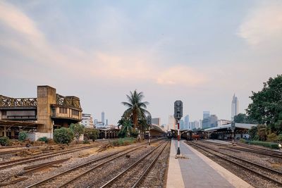 Railroad tracks by buildings in city against sky