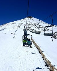 Ski lift over snowcapped mountains against clear sky