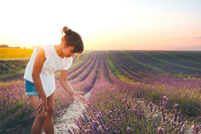 Woman standing on field against sky during sunset