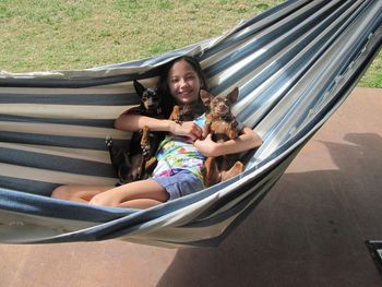 Portrait of smiling girl with dogs relaxing in hammock