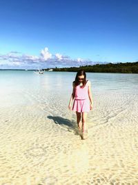 Young woman walking at beach on sunny day