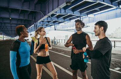 Friends drinking juices while standing on road in city