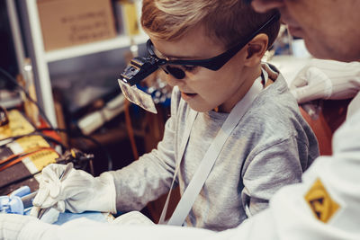 Engineering teacher and small boy repairing computer part in it lab.