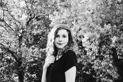 Portrait of young woman against trees