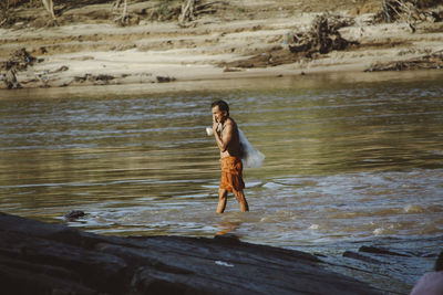 Full length of shirtless man in water at beach