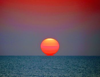 Scenic view of sunrise sunset over sea against orange sky horizon.