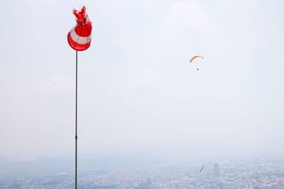 Low angle view of windsock against parachute in sky