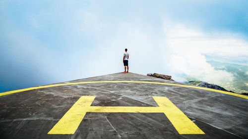 Rear view of man standing on helicopter platform in the mountains