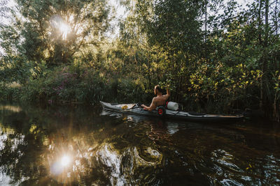 People on lake amidst trees in forest