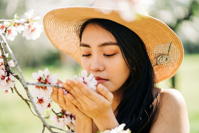 Close-up portrait of young woman with pink flowers