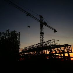 Low angle view of silhouette cranes against sky during sunset