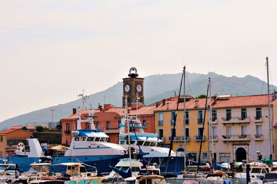 Boats moored at harbor against sky