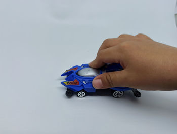 Close-up of hand holding toy car over white background