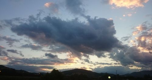 Scenic view of mountains against cloudy sky at sunset