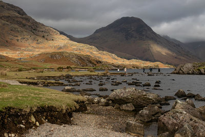 Family/friends using stepping stones from the stone island back to shore at wastwater