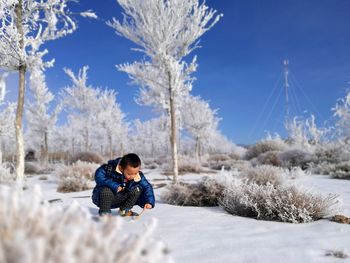 Little boy crouching on snow covered field