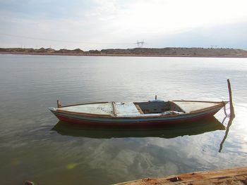 Boat moored on lake against sky