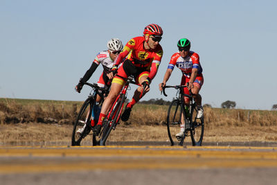 People riding bicycle on field against clear sky