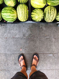 Low section of man standing on tiled floor with melons