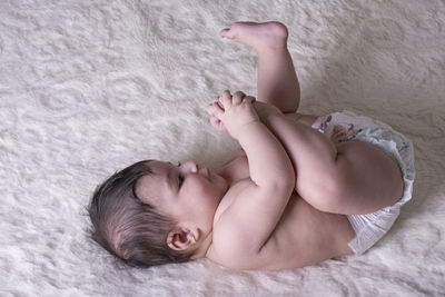 Directly above shot of shirtless baby girl lying on bed