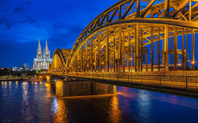 Illuminated hohenzollern bridge over rhine river against cologne cathedral